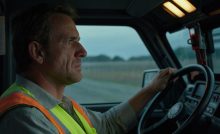 A DOT truck driver sitting in a commercial truck.